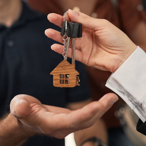 Image shows a close up two hands, handing over house keys