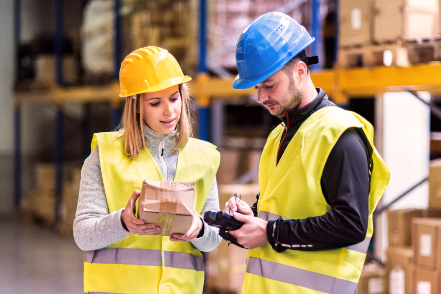 Two people wearing hard hats and high vis vests looking at a parcel